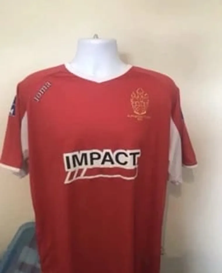 Red IMPACT football shirt on a mannequin